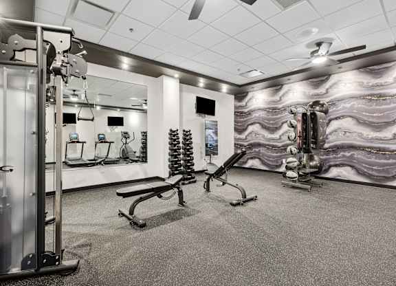 A gym with a variety of equipment including a squat rack, bench, and weights.