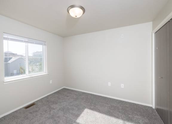 A room with a window and a carpet on the floor.