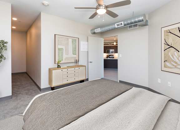 A bedroom with a bed, dresser, and ceiling fan.