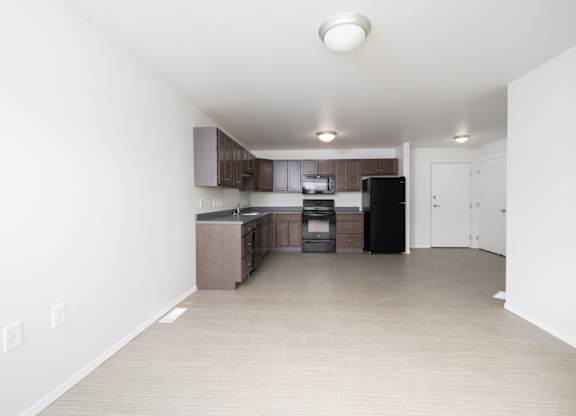 A kitchen with a black fridge and white walls.
