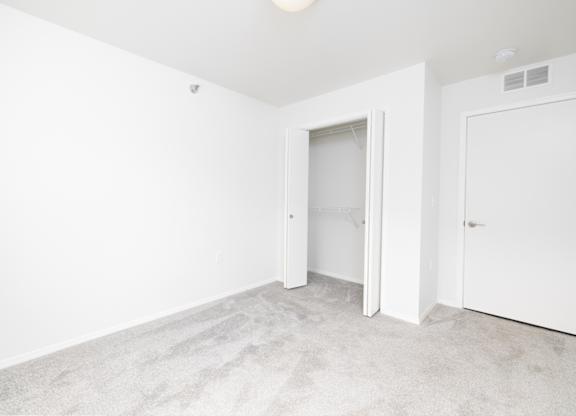 A white room with a carpeted floor and two doors.