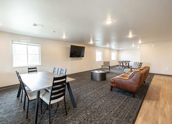 A conference room with a table, chairs, and a television.