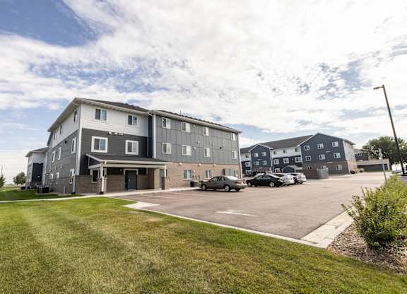 A large grey building with a parking lot in front.