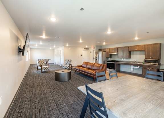 A modern living room with a brown leather couch and a wooden floor.