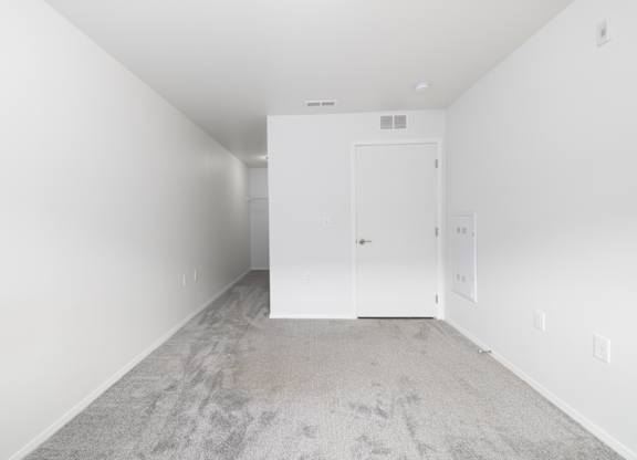 A room with a carpeted floor and a white door.