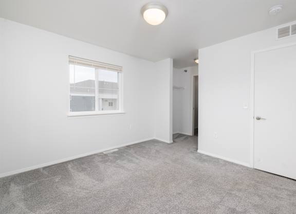 A room with a carpeted floor and a window.