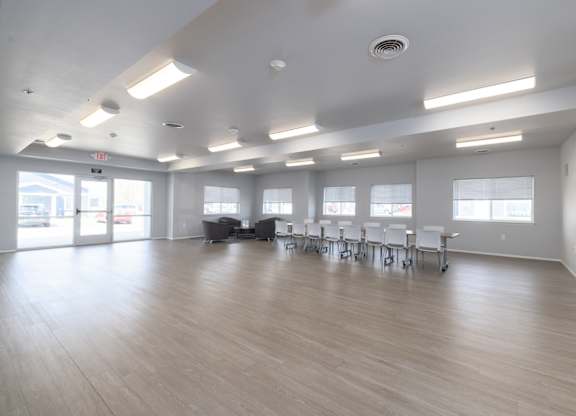 A large room with tables and chairs and a door.