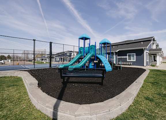 A playground with a blue slide and a black bench.