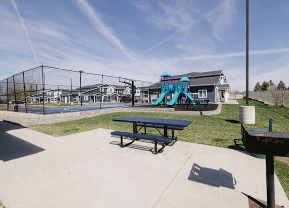 A playground with a blue slide and picnic tables.