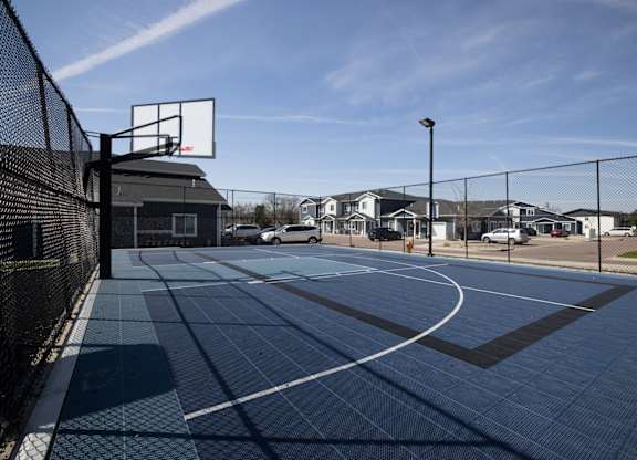A basketball court with a black fence and a basketball hoop.