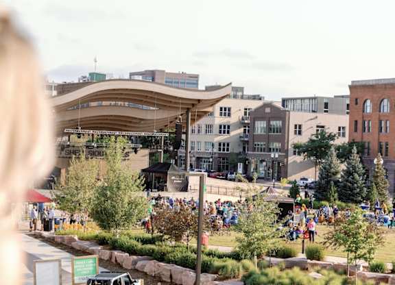 A woman with blonde hair is looking at a park with people walking around.