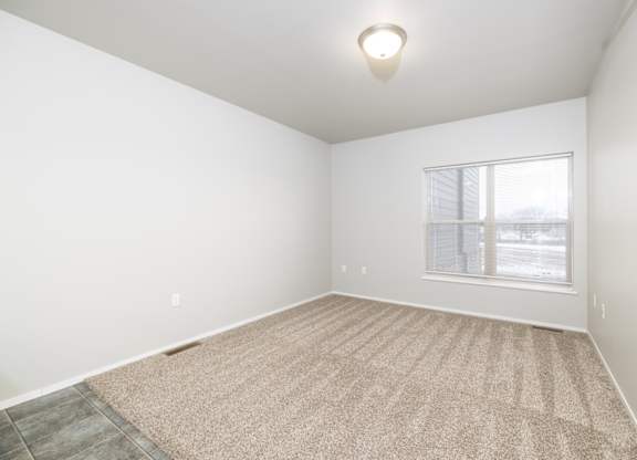 A room with a carpeted floor and a window.