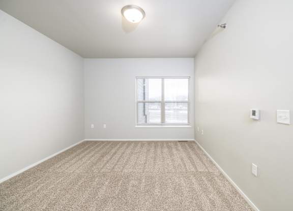 A room with a carpeted floor and a window.