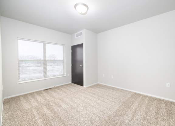 A room with a carpeted floor and a door.
