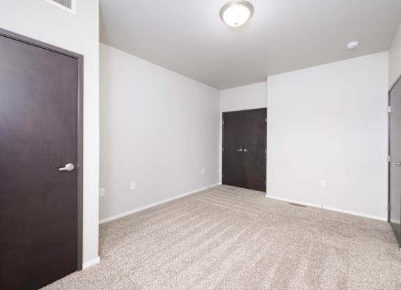 A room with a carpeted floor and two doors.