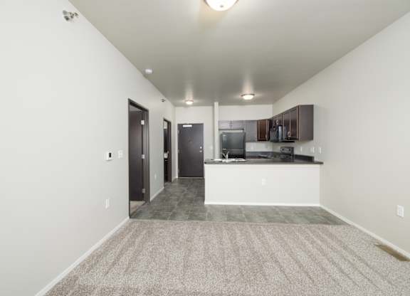 A spacious living room with a kitchen area in the background.