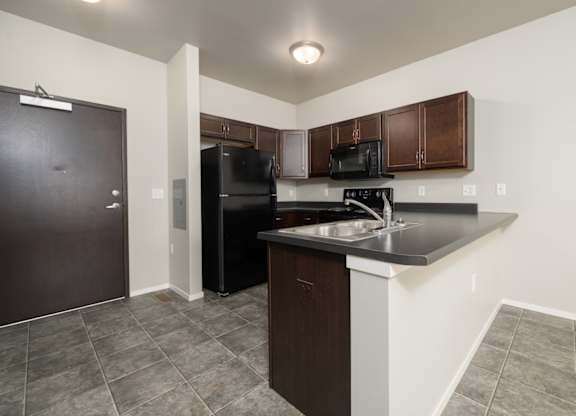 A kitchen with black appliances and brown cabinets.