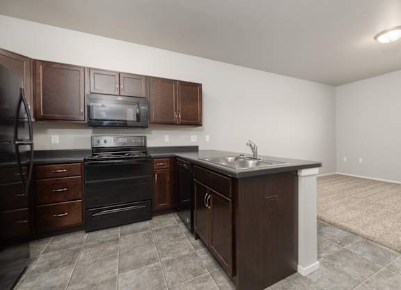 A kitchen with brown cabinets and a black refrigerator.