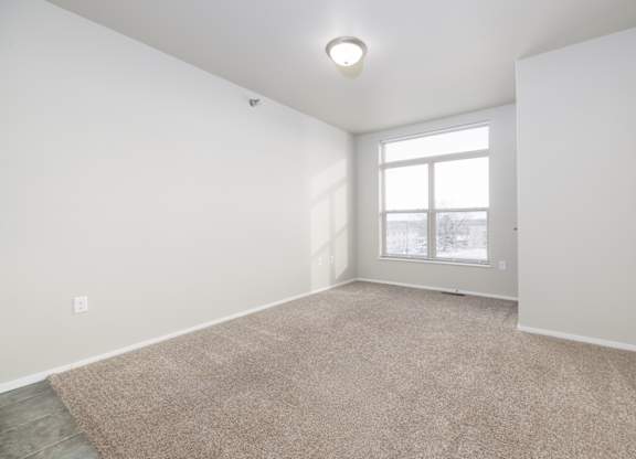 A room with a carpeted floor and a window.