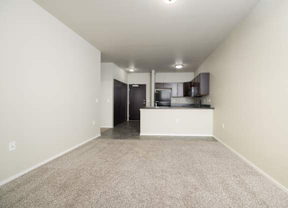 A spacious room with a kitchen area in the background.