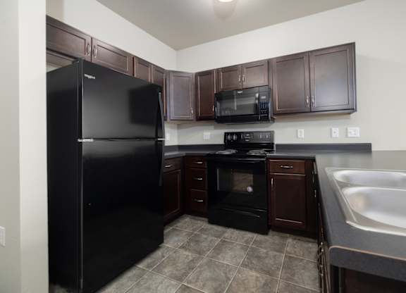 A kitchen with black appliances and brown cabinets.
