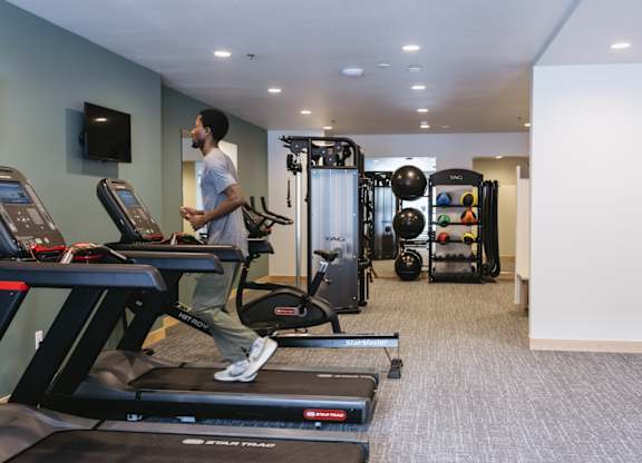 A man is running on a treadmill in a gym.