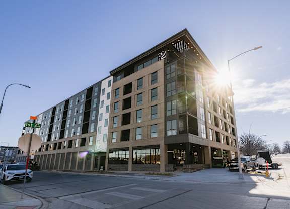 A modern building with a glass facade is bathed in sunlight.