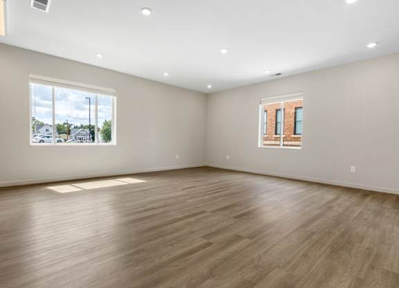 A large empty room with wooden flooring and a window.