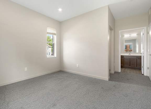 A spacious room with a carpeted floor and a window.