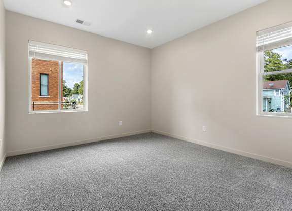 A room with a window showing a brick building outside.