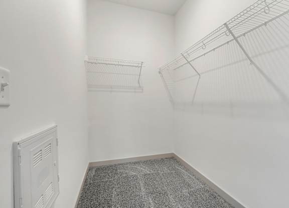 A white wall with a wire shelf and a vent.