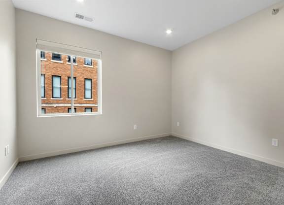 A room with a large window and a view of a brick building outside.