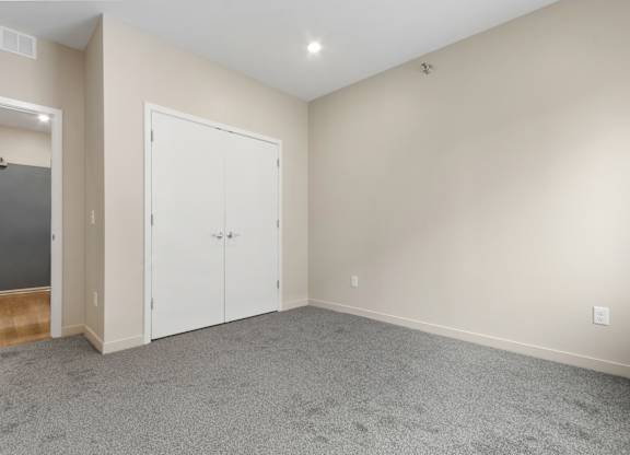A room with a carpeted floor and two white doors.