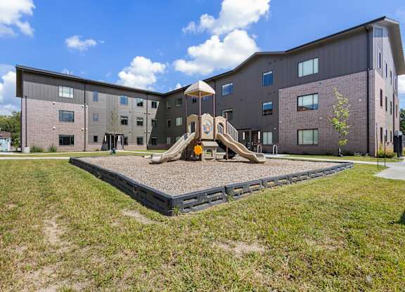 A playground area in front of a modern building.