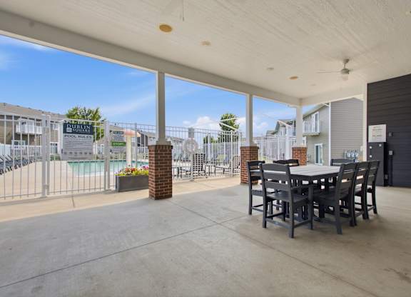 A patio with a table and chairs overlooking a pool.