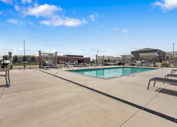 A large outdoor swimming pool with a concrete deck and a building in the background.