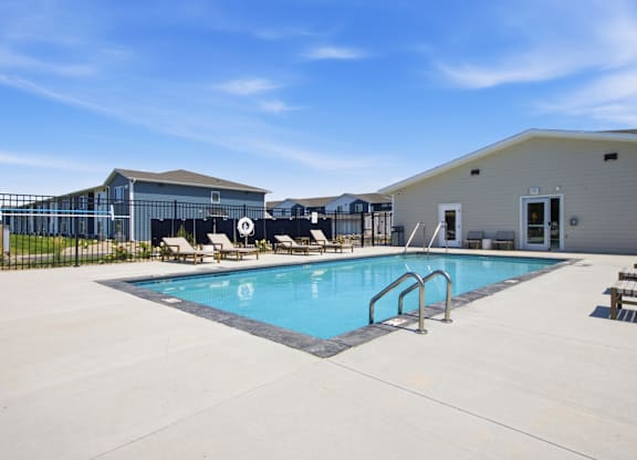 A pool with a metal ladder and a fence with a gate.