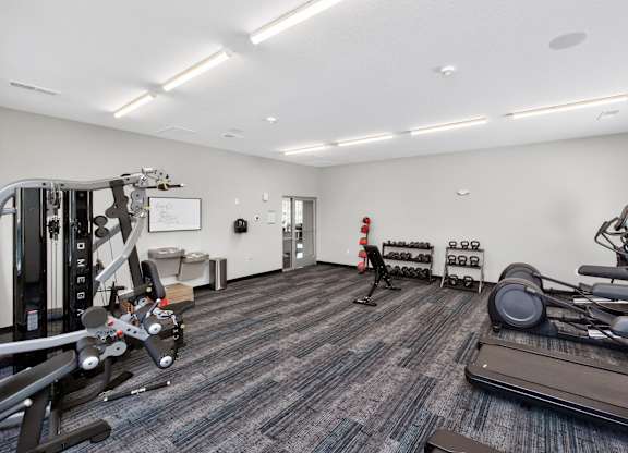 A gym with a variety of equipment including treadmills, weights, and exercise machines.