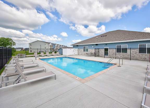 A swimming pool surrounded by a concrete patio and metal railings.