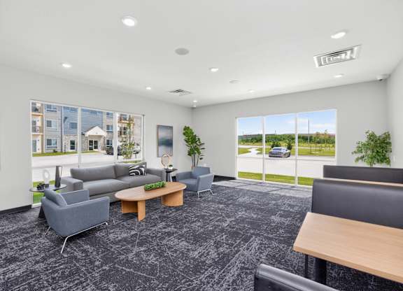A spacious waiting room with grey and black furniture and a large window showing the outside.