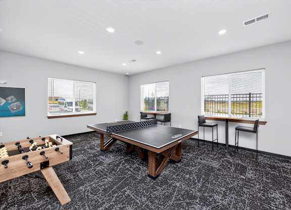 A room with a foosball table, a couch, and a table with chairs.