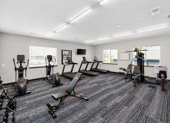 A gym with a variety of equipment including treadmills, weights, and exercise machines.