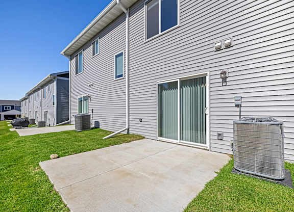 A building with a grey siding and a grey air conditioning unit in front.