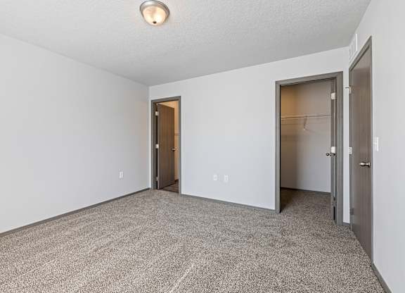 A carpeted room with a doorway leading to another room.