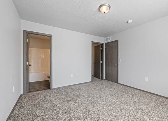 A room with a carpeted floor and two doors.