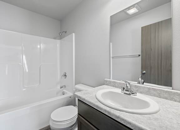 A white bathroom with a toilet, sink, and bathtub.