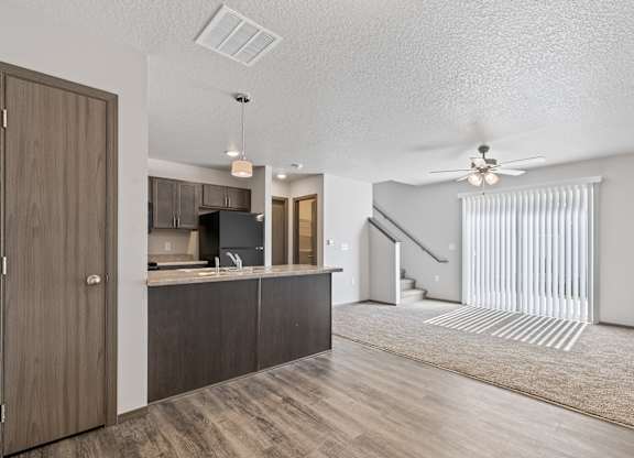A modern kitchen with wooden cabinets and a staircase in the background.