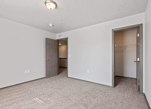 A room with a carpeted floor and two doors, one of which is open.