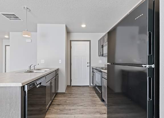 A kitchen with a black refrigerator and a white door.