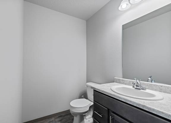 A bathroom with a toilet, sink, and mirror.